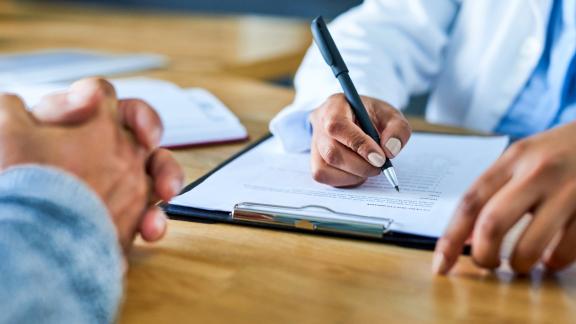 Doctor filling in form with patient