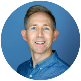 A photo of Rich Andrews, wearing a blue shirt against a blue background.