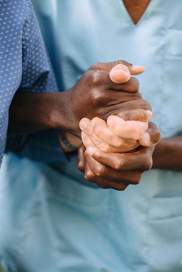 A carer supporting a patient with their arms locked together.