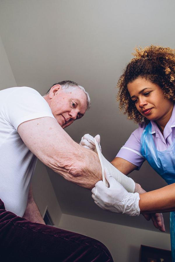 A community nurse applying a bandage to a patient.