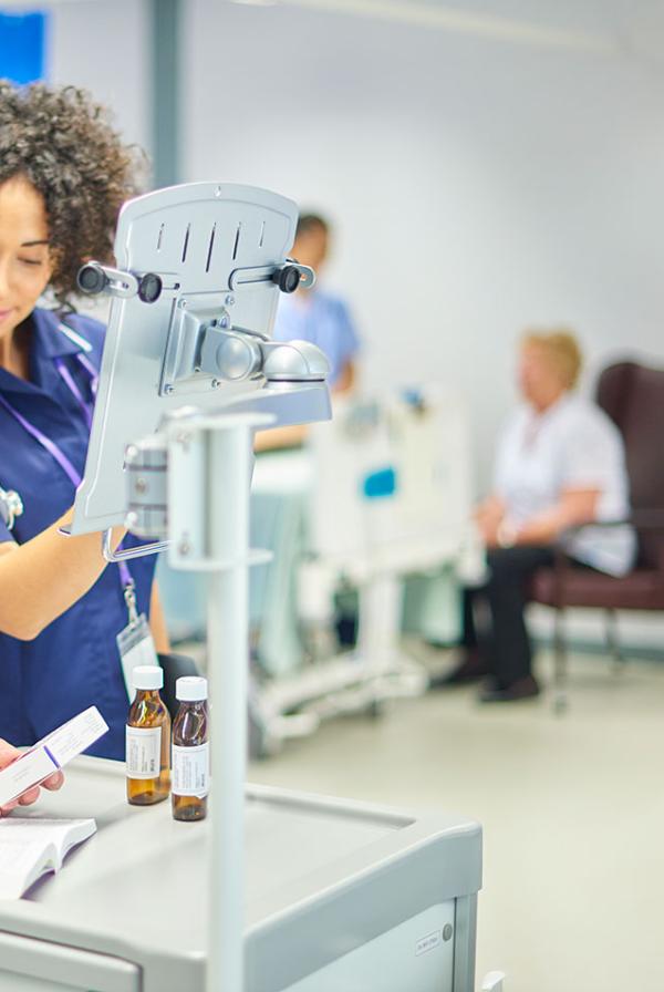 Healthcare staff on a ward, checking medicine against a computer.