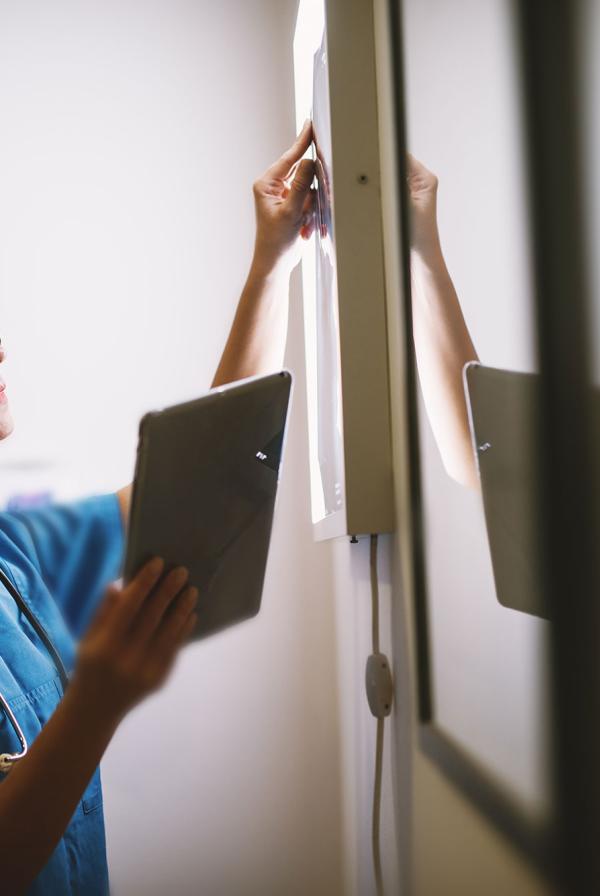 A radiographer holding a tablet, looking at a scan.