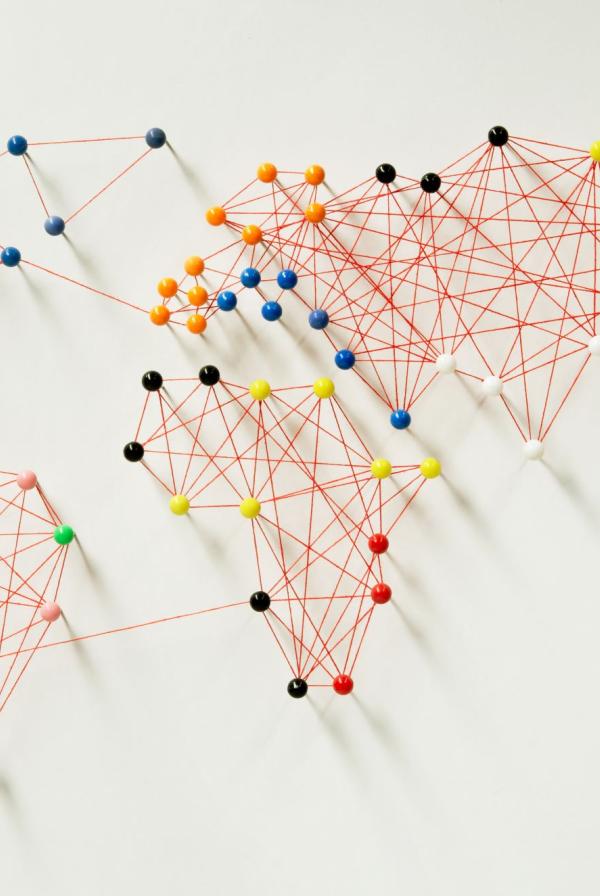 Multicoloured pins and string which connect up to form world map