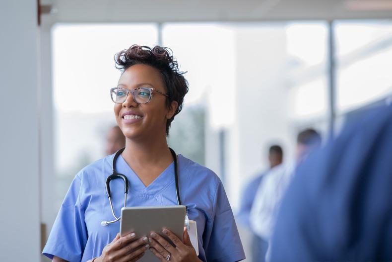 A smiling doctor holding a tablet computer.